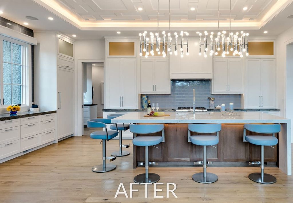 After photo of modern kitchen remodel. With blue chairs at the island. Island has an inset sink. White cabinets with oak flooring. Modern light fixture over it all.