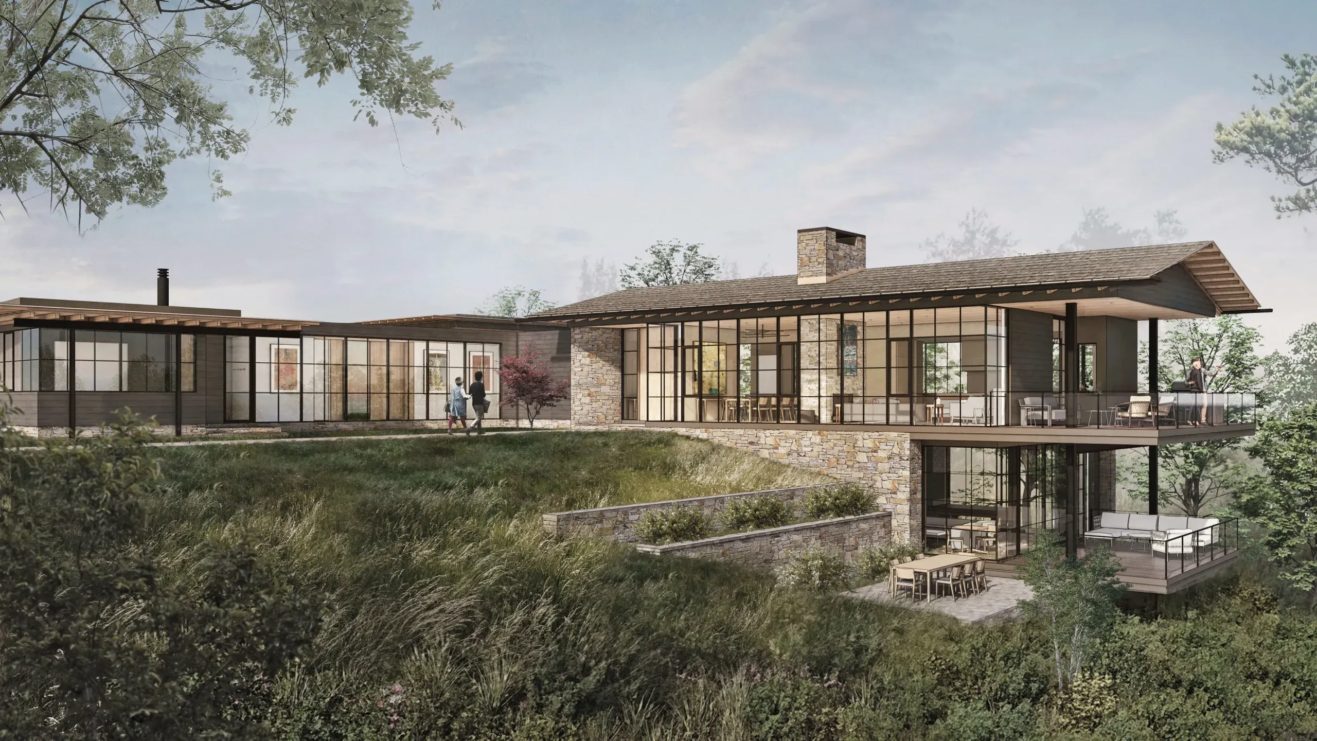 Modern hillside home with large glass windows, stone walls, and tiered outdoor decks.