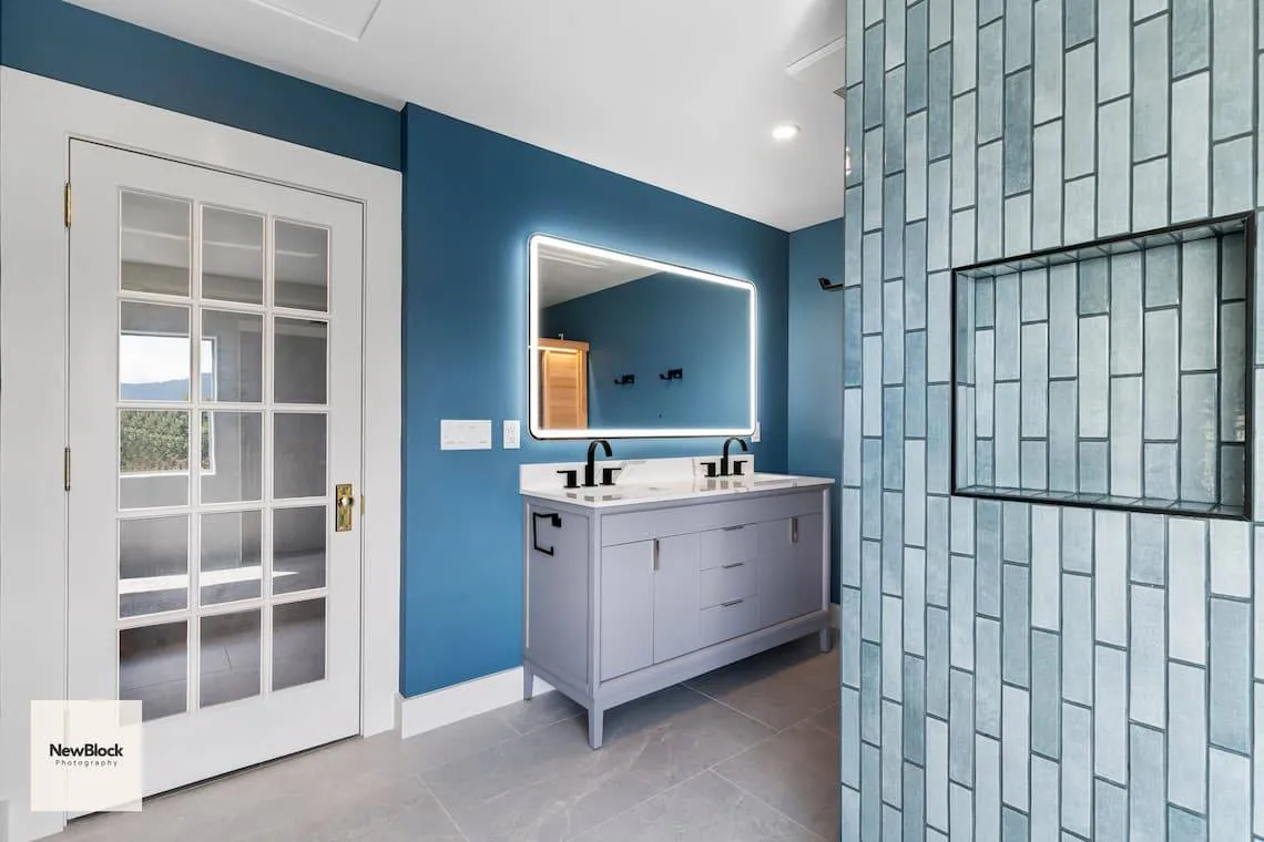 Double vanity with lighted mirror and blue walls.