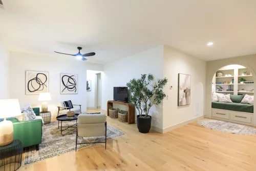 Sitting room with green seating, black accent chairs, abstract artwork, and an arched reading nook with built-in shelves.