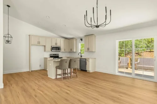 Kitchen with light cabinetry, breakfast bar, and sliding glass doors to deck.