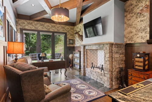 Den with stone fireplace, chairs, and flat screen TV.