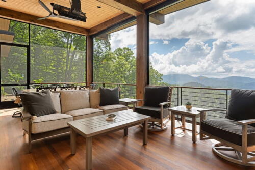 Porch with couches and chairs overlooking stunning view of the mountains.