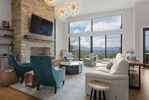 Living room with large windows, glass chandeliers, fireplace and seating area.