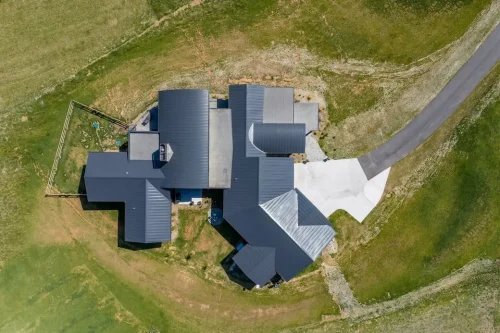 Overhead aerial view of the home showing its expansive dark metal roof and surrounding property.