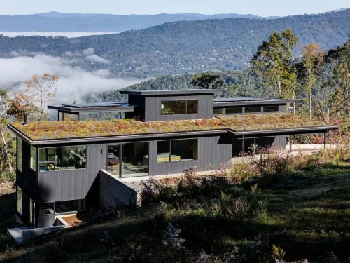 Modern mountain home with a green roof overlooking layered Blue Ridge Mountains and morning fog