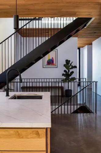 Interior stair detail with black metal railing, wood ceiling, and modern artwork