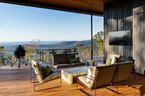 Covered outdoor deck with seating area, grill, and panoramic mountain views