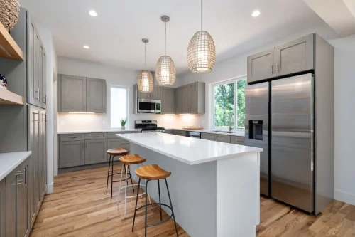 Spacious kitchen with gray cabinets, quartz countertops, stainless steel appliances, and pendant lighting.