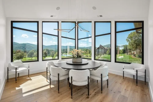 Dining nook with floor-to-ceiling corner windows and panoramic views of mountains and golf course.