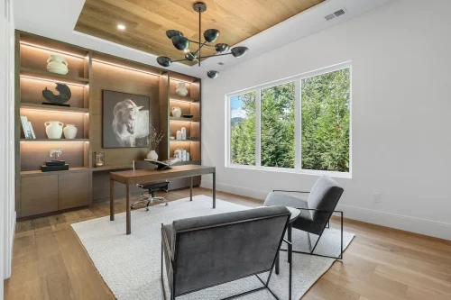 Home office with built-in shelving, wood ceiling, and large window.