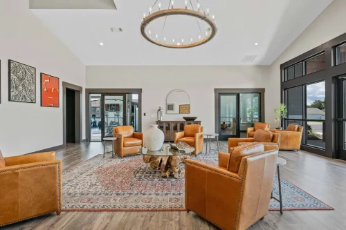 Clubhouse lounge with leather chairs, rug, and circular chandelier