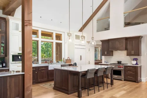 Gourmet kitchen with dark wood cabinetry, white quartz countertops, pendant lights, and a central island with seating beneath high ceilings.