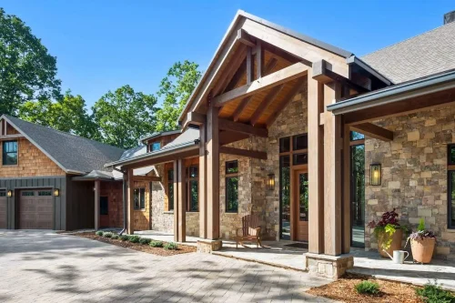 Craftsman-style entry with stone and wood siding, exposed beams, and covered porch leading to a warm mountain retreat.