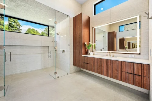 Contemporary bathroom with floating wood vanity, large mirror, and glass walk-in shower.