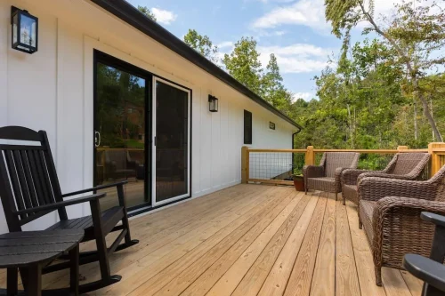 Restored back deck with black rocking chairs and wicker seating.