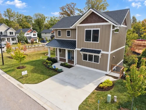 Aerial front view showing the home’s gabled roof, covered entry, landscaped yard, and driveway.