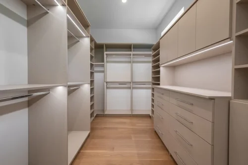 Custom walk-in closet featuring built-in shelving, hanging rods, drawers, overhead cabinets, and integrated lighting.
