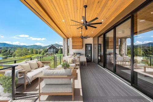 Covered porch with wood ceiling, ceiling fans, and outdoor seating overlooking rolling hills and golf course.