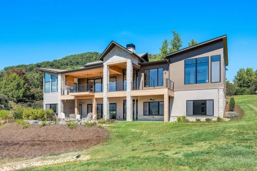 Back exterior of a contemporary home with expansive windows, double-level patios, and outdoor living space.