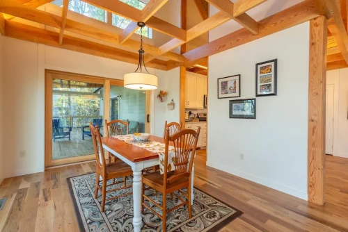 Dining area with exposed wood beams and sliding glass doors opening to a covered deck.