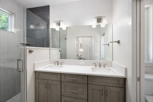 Bathroom with dual vanity, quartz countertop, and walk-in shower with hex tile accent wall.