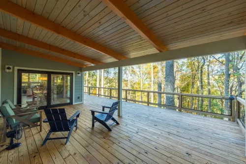Covered wood deck with outdoor seating overlooking the surrounding forest.