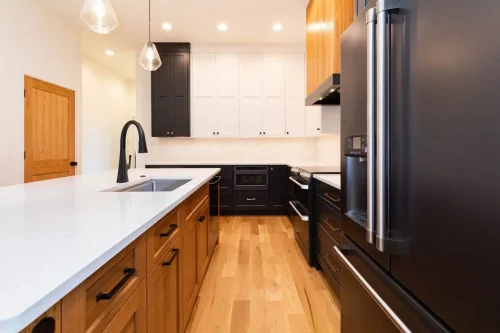Modern kitchen with wood and black cabinetry, white countertops, black appliances, and a large island.