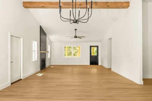 Open living room with wood floors, vaulted ceiling, and black fireplace.