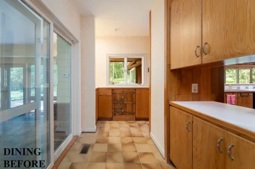 Dining area before renovation featuring wood cabinetry, beige tile flooring, and large sliding glass doors.