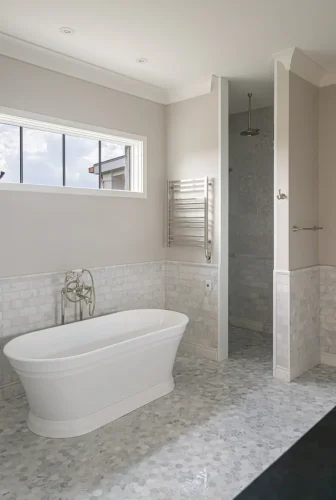Luxury bath with freestanding white soaking tub, marble tile walls and floors, and walk-in shower with rainfall showerhead.