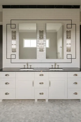 Bright owner’s bath with custom white double vanity, marble counters, chrome fixtures, and tiled feature wall with geometric accents.
