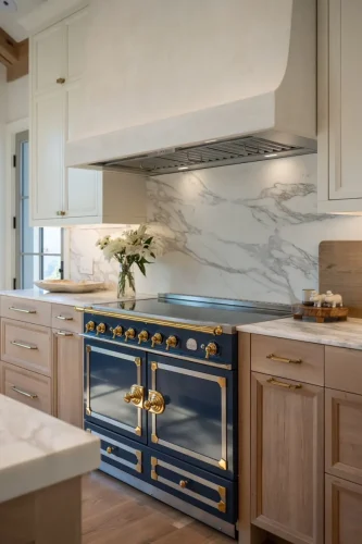 Navy blue range with brass accents, marble backsplash, custom plaster range hood, and natural wood cabinetry.