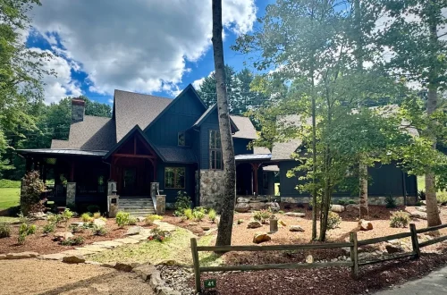 Dark-sided craftsman-style mountain home with stone accents and landscaped front yard.