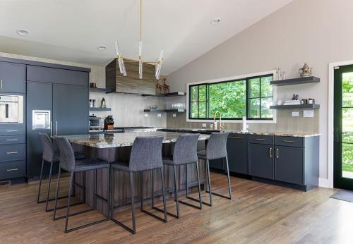 Remodeled kitchen, with dark blue cabinets. Very open space, with large island in the middle surrounded by tall chairs. 