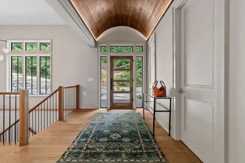 Bright entryway with a wood-paneled barrel-vault ceiling, wood front door, large windows, and hardwood flooring.