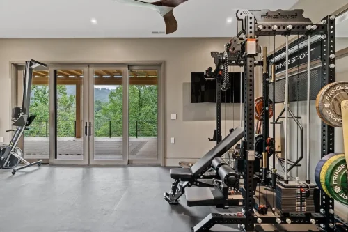 Home gym with strength-training equipment and glass doors opening to a covered outdoor living area.