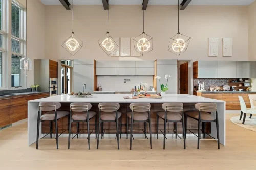 Modern kitchen with an oversized waterfall island, wood and light cabinetry, pendant lighting, and seating for six.