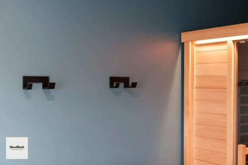 Two black wall hooks beside wooden sauna.