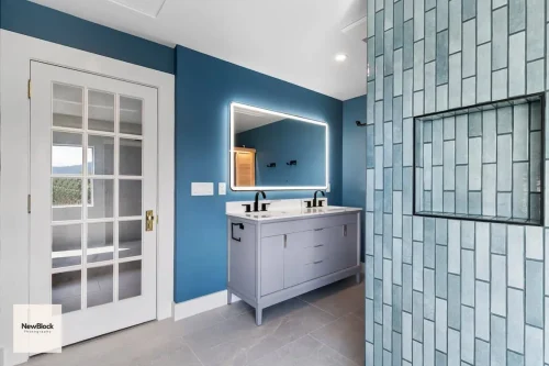 Double vanity with lighted mirror and blue walls.