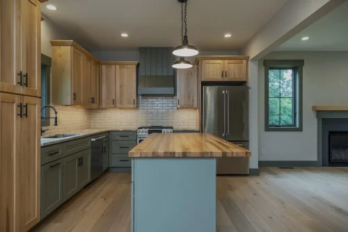 Kitchen with two-tone cabinetry, butcher block island, subway tile backsplash, and stainless steel appliances.