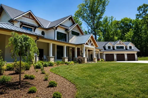 Front view of a craftsman-style home with multiple gables, stone accents, covered porches, and an attached three-car garage.