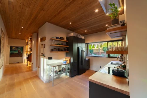 Kitchen with dark cabinetry, wood countertops, open shelving, a black refrigerator, and a wood-paneled ceiling.