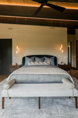 Contemporary bedroom with upholstered bed, pendant lights, and a bench at the foot of the bed.