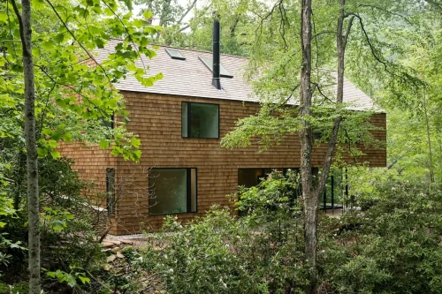 Wood-shingled home exterior nestled in the forest.