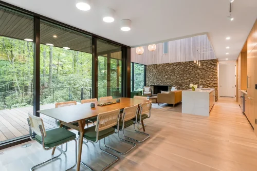 Dining area with large windows overlooking wooded views.