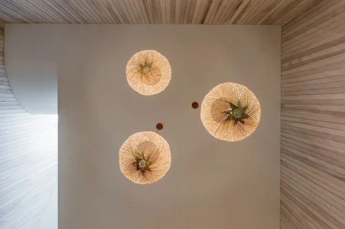 Three woven pendant lights hanging from a high ceiling.