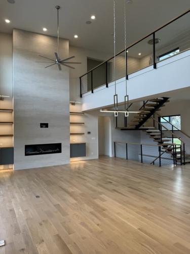The Elie Residence great room with wood floor, fireplace, and view of loft.