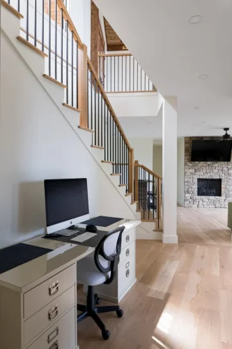 Home office nook with desk and computer beneath modern staircase.