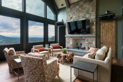 Mountain-view porch with stone fireplace, TV, and comfortable seating.
